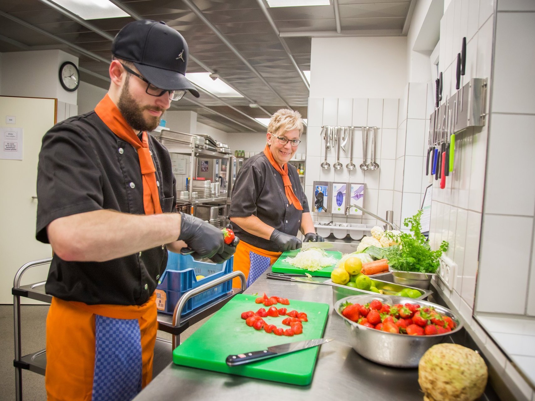 In der Küche: eine Köchin und ein Koch schneiden Obst und Salat