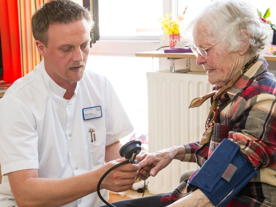 Ein Pfleger misst den Blutdruck bei einer älteren Frau