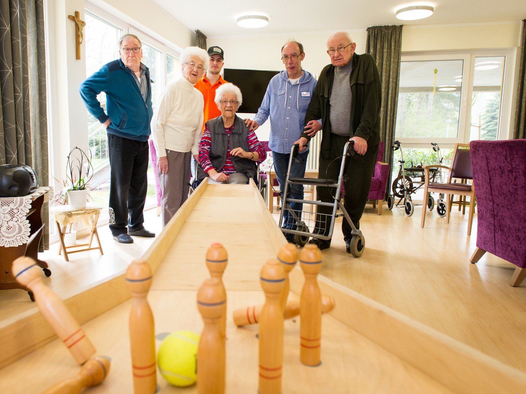 Fünf Bewohner kegeln mit einer mini Kegelbahn aus Holz und einem Tennisball