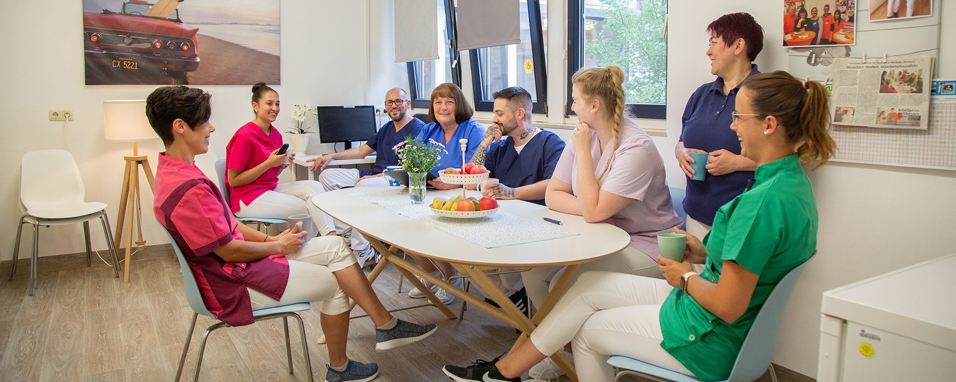 Im Besprechungsraum: Mitarbeiter sitzen an einem ovalen Tisch und besprechen sich - scheint lustig zu sein
